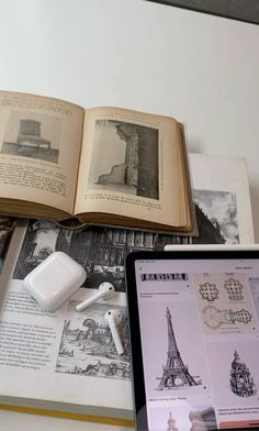 an open book sitting on top of a table next to headphones and other items