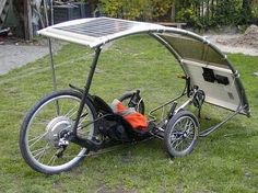 a bike with a solar panel attached to the front wheel and back tire, parked on grass