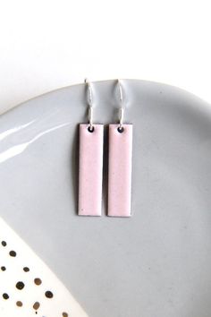 Soft pastel pink earrings handmade by firing enamel onto copper in a kiln at a temperature of over 800 degrees. The geometric rectangular earrings measure approximately 30mm x 8mm and would make a fab gift for any lover of stylish jewellery accessories. These earrings are backed with counter enamel to insure comfort and strength. They come complete with 925 Sterling silver earring wires and would look fabulous with any outfit all year round. CUSTOMISE: Please contact me if you would like a bespo Modern Pink Rectangular Earrings, Rectangular Pink Earrings For Gifts, Pink Rectangular Earrings As Gift, Pink Rectangular Earrings For Gift, Pink Rectangular Earrings For Gifts, Pink Square Jewelry Gift, Pink Square Jewelry For Gifts, Handmade Minimalist Pink Earrings, Handmade Square Pink Jewelry