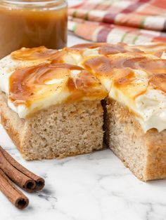 a close up of a cake on a table with cinnamon sticks and a cup of coffee