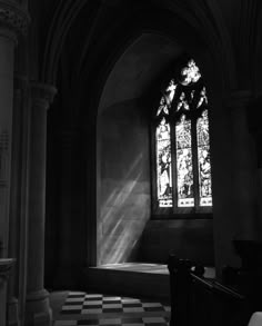 the sun shines through a stained glass window in an old church with black and white checkered flooring