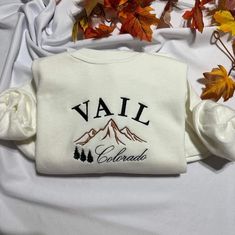 Stay warm and look stylish with this unique Vail Colorado embroidered  at the center of the chest This piece of clothing is perfect for any casual occasion. The high-quality fabric keeps you warm and comfortable, while the intricate embroidery brings a touch of elegance and charm to any ensemble. Whether you're out and about or just lounging at home, this sweatshirt is sure to make you stand out from the crowd. The sweatshirt also features a classic crew neckline and long sleeves for a timeless look. It's available in a range of sizes and colors, so you're sure to find the perfect one to suit your style. Plus, it's easy to care for, making it the perfect addition to your wardrobe. Product Benefits: * Stylish and fashionable  * Comfortable and warm * Unique embroidered pattern * Classic cre White Embroidered Logo Sweater For Fall, White Letter Embroidery Sweatshirt For Fall, White Letter Embroidery Sweater For Fall, White Sweater With Custom Embroidery For Fall, Crew Neck Sweatshirt With Letter Embroidery For Winter, Embroidered Crew Sweater For Winter, White Embroidered Sweatshirt For Fall, Long Sleeve Sweatshirt For Fall Gift, Cotton Sweater As Fall Gift