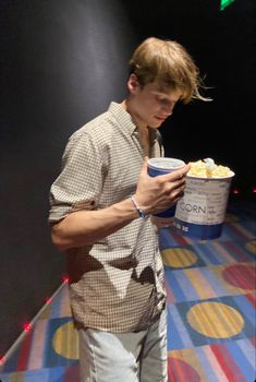 a young man holding a bucket of popcorn