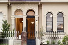 a large white house with arched windows and wrought iron fence