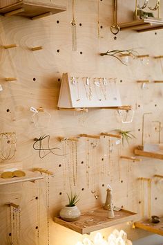 there are many necklaces hanging on the wall in this room with wooden shelving