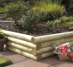 a wooden planter sitting on top of a sidewalk next to a flower bed and potted plants