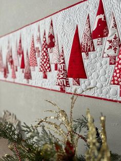 a wall hanging decorated with red and white christmas trees