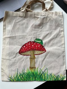 Hand painted tote bag. Cute frog on mushroom. Canvas bag. Custom painted. Handmade. frog. mushroom.  *note: painting is not finished yet* Tote Bags Painting, Totebag Painting, Frog On Mushroom, Mushroom Canvas, Painted Tote Bag, Frog Mushroom, Painted Tote