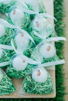 golf balls wrapped in clear cellophane and tied with ribbon on top of green grass