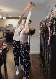 two people are doing yoga in the living room with christmas decorations on the wall behind them