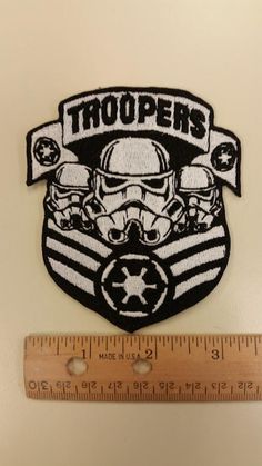 a patch with the words troopers on it and a star wars helmet in front of a ruler