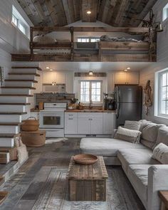 a living room filled with furniture next to a kitchen and stairway leading up to a loft