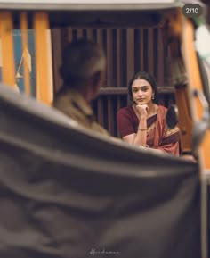 a woman sitting in front of a mirror with her hand on her chin looking at herself