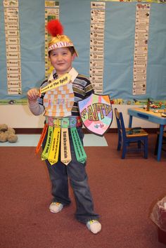 a young boy wearing a costume made out of ties and paper machs, standing in a classroom