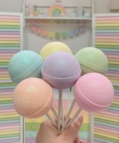 a hand is holding several candy lollipops in front of a rainbow background