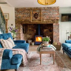 a living room filled with blue couches and a fire place in the middle of it