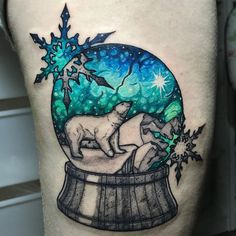 a man's thigh with a snow globe and two dogs in it on his leg