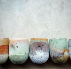 five different colored coffee cups lined up in a row on top of eachother