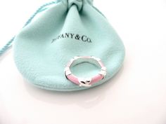 Overview:Everyone needs a signature Tiffany piece! Here is the ultimate Tiffany Signature piece just for you! Offered for sale is a wonderful and mint Tiffany & Co. Sterling Silver and Pink Enamel Signature Ring. The piece is crafted from bright and substantial Tiffany silver, and yet retains a feminine and delicate feel to it. It is a wonderful ring that fits a lifestyle on the go -- can be worn to almost any occasion! It is simple, elegant, and classic all rolled into one item. Imagine the pie Tiffany Melody Ring, Signature Ring, X Ring, Signature Rings, Pink Enamel, Gift Pouch, Ring Band, Love Gifts, Tiffany & Co.