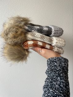 a person holding four knitted scarves with fur on them, all in different colors