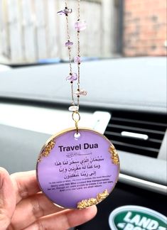 a person is holding up a travel dua in their hand and it's attached to the dashboard of a car