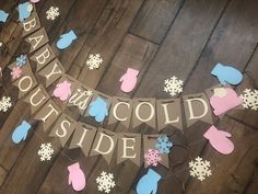 baby it's cold outside banner with mittens and snowflakes hanging on a wood floor