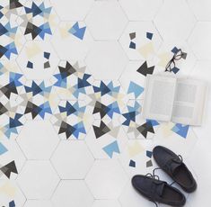 a pair of black shoes sitting on top of a floor next to an open book