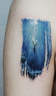 a man with a tattoo on his arm that has an image of a person swimming in the water