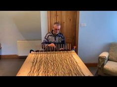 a man is playing an instrument in front of a table with wood carvings on it