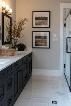 a bathroom with two framed pictures on the wall and marble counter tops, along with a walk in shower