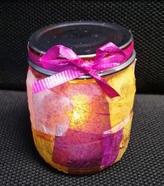 a painted jar with a purple ribbon tied around it