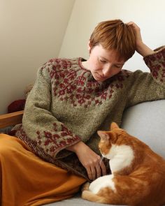 a woman sitting on top of a couch next to an orange and white cat in her lap