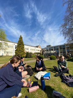 several people sitting on the grass in front of a building