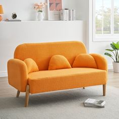 an orange couch sitting on top of a white rug