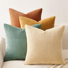 four pillows sitting on top of a white couch next to each other in different colors