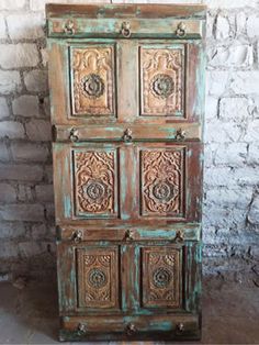 an old wooden cabinet with ornate carvings on the front and sides, against a brick wall