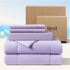 a stack of purple sheets and pillows next to a box with the rest logo on it