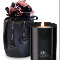 a black candle with a pink ribbon on it next to a black bag that says coya