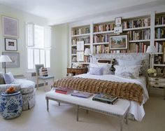 a bed sitting in a bedroom next to a chair and book shelf filled with books