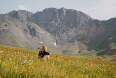 a woman standing on top of a lush green hillside