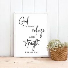 a white framed sign with the words god is our refuge and strength on it next to a potted plant