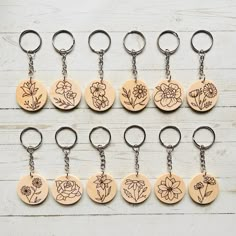 six wooden keychains with flowers on them are lined up against a white background