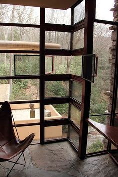 a chair sitting on top of a stone floor next to a window filled with lots of windows