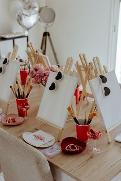 the table is set up with easels and cups for art class or birthday party