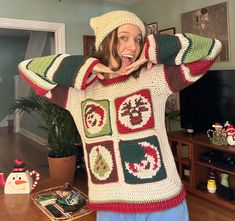 a woman wearing a crocheted sweater and hat with her hands behind her head