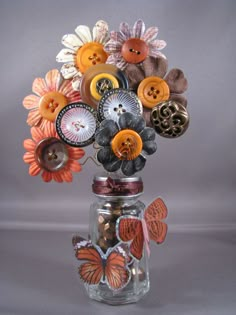 a vase filled with lots of different types of buttons on top of a glass jar