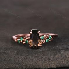 a close up of a ring on a rock with green stones and leaves around it