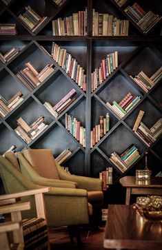 a living room filled with lots of books and furniture next to a wall covered in shelves