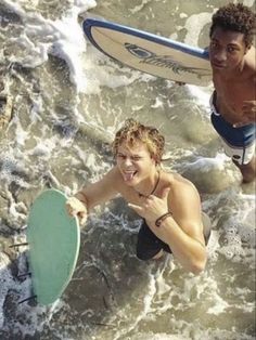 two men are in the water with surfboards and one is holding a frisbee