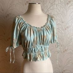 Milkmaid Crop By Shabby Chic Can Be Worn Off Shoulder Corset Style Puffy 3/4 Sleeves Blue/Greenish Color With Neutral Colored Roses Bridgerton Vibes Tag Says Medium But Can Fit Small As Well Mannequin Wears Small, 34b Bust, 27” Waist Brand New Items Will Be Stated.All Preloved And Vintage Items Sold As Is. Please Message Me With Any Questions For We Always Try To Give You The Best Description But Unfortunately As Humans We Might Miss A Thing Or Two. Vintage Items Are Always Hand Selected With Lo Fitted Half Sleeve Beach Tops, Fitted Floral Print Blouse With Half Sleeves, Fitted Half Sleeve Floral Print Blouse, Fitted Half Sleeve Floral Blouse, Summer Ruffle Half Sleeve Blouse, Light Blue Cropped Summer Blouse, Blue Fitted Half-sleeve Blouse, Summer Half Sleeve Blouse With Ruffles, Light Blue Cropped Blouse For Summer